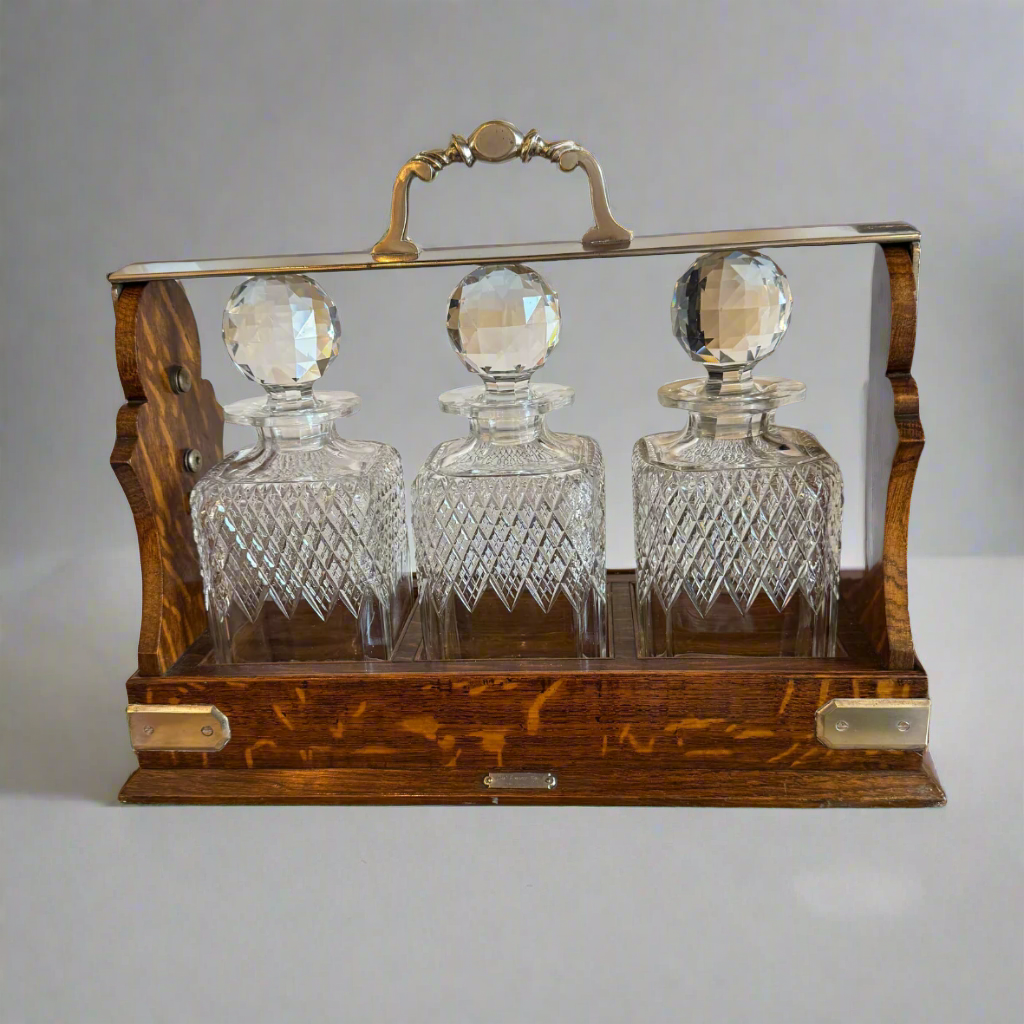 Betjemanns patent oak and silver plated three bottle tantalum retailed by Asprey of London. Extra quality cut glass decanters with  facet cut stoppers. Original Bramah lock and two keys